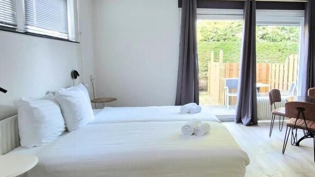 Une chambre d’hôtel avec un grand lit, une petite table, une chaise et une vue sur l’extérieur.