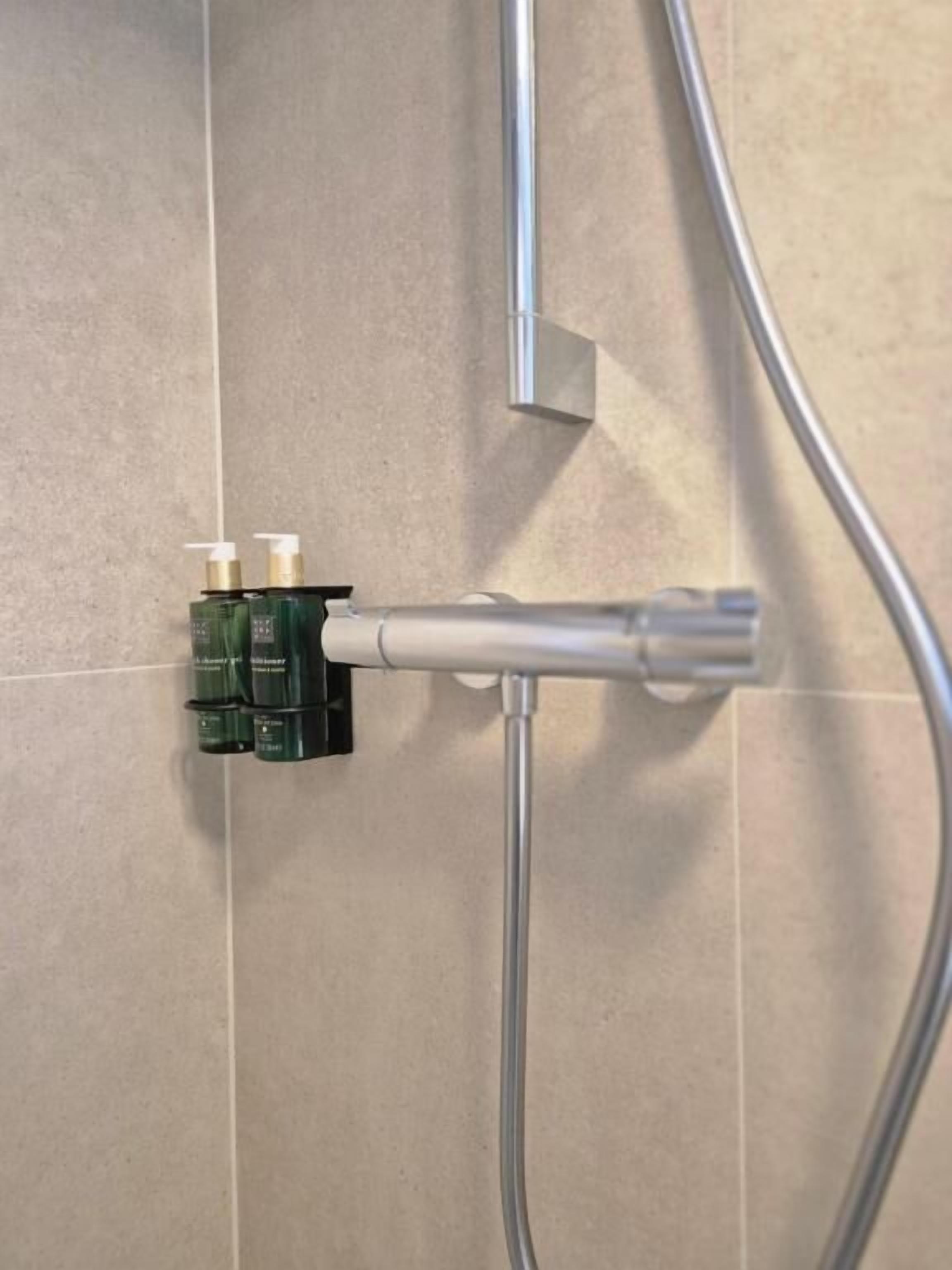 A shower with a handheld showerhead and a wall-mounted control valve.