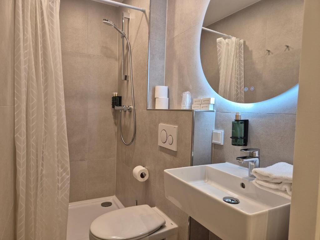 Un baño moderno con ducha, inodoro, lavabo y espejo.