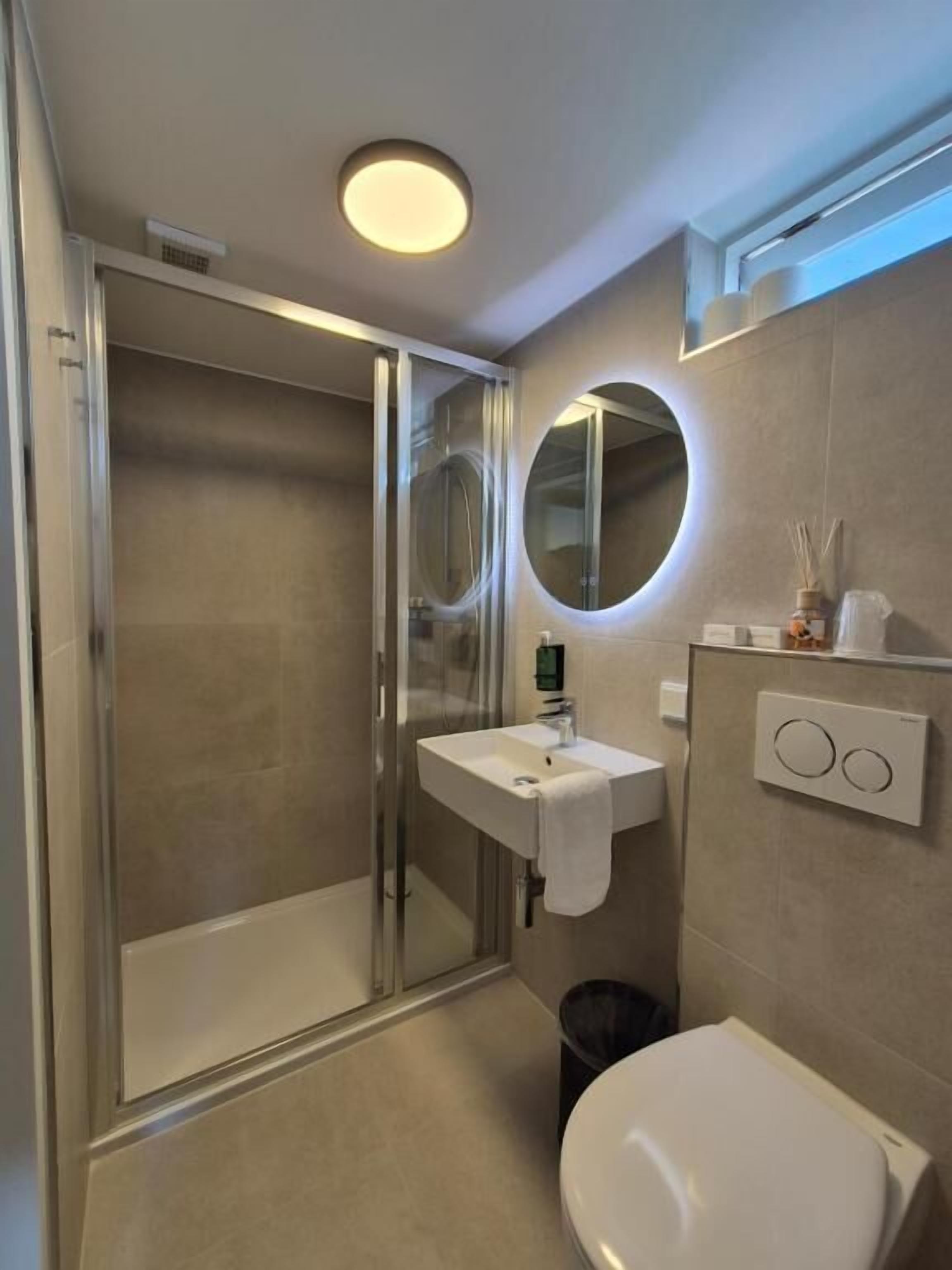 A modern bathroom with a glass shower enclosure, a white sink, and a toilet.