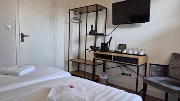A hotel room with a bed, a desk with a computer, a TV, and a chair.