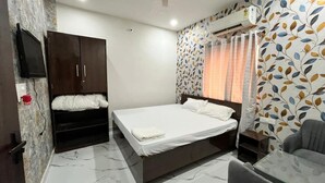 A bedroom with a bed, wardrobe, TV, air conditioning unit, and patterned wallpaper. - Sunrise Prime (Ranchi)