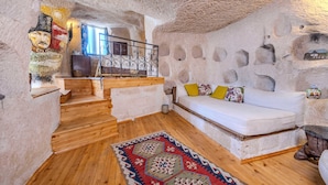 Un interior acogedor con una escalera de madera, un sofá blanco con cojines de colores y una alfombra estampada.