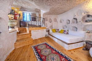 A cozy interior with a wooden staircase, a white sofa with colorful cushions, and a patterned rug.
