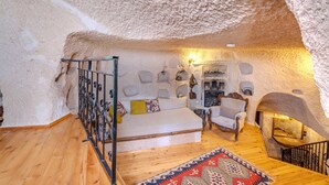 Un interior acogedor con una pared de piedra, un sofá, una silla, un tapete estampado y una chimenea.