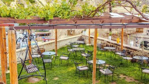 Un patio exterior con varias mesas y sillas, una hamaca y un pérgola.