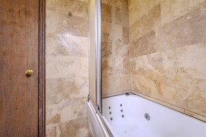 Un bagno con una vasca, una porta in legno e pareti in pietra.