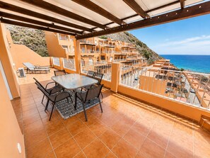 A terrace with a table and chairs, overlooking a coastal area with buildings and a view of the sea. - Seagull Lookout (Mojácar)