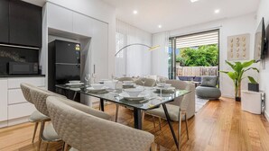 Una cucina moderna con forno integrato, una zona pranzo con tavolo in vetro e un angolo relax con divano e poltrone.