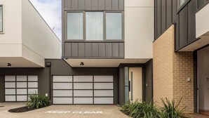 Un edificio residenziale moderno su due piani con garage, un muro in mattoni e un vialetto libero.
