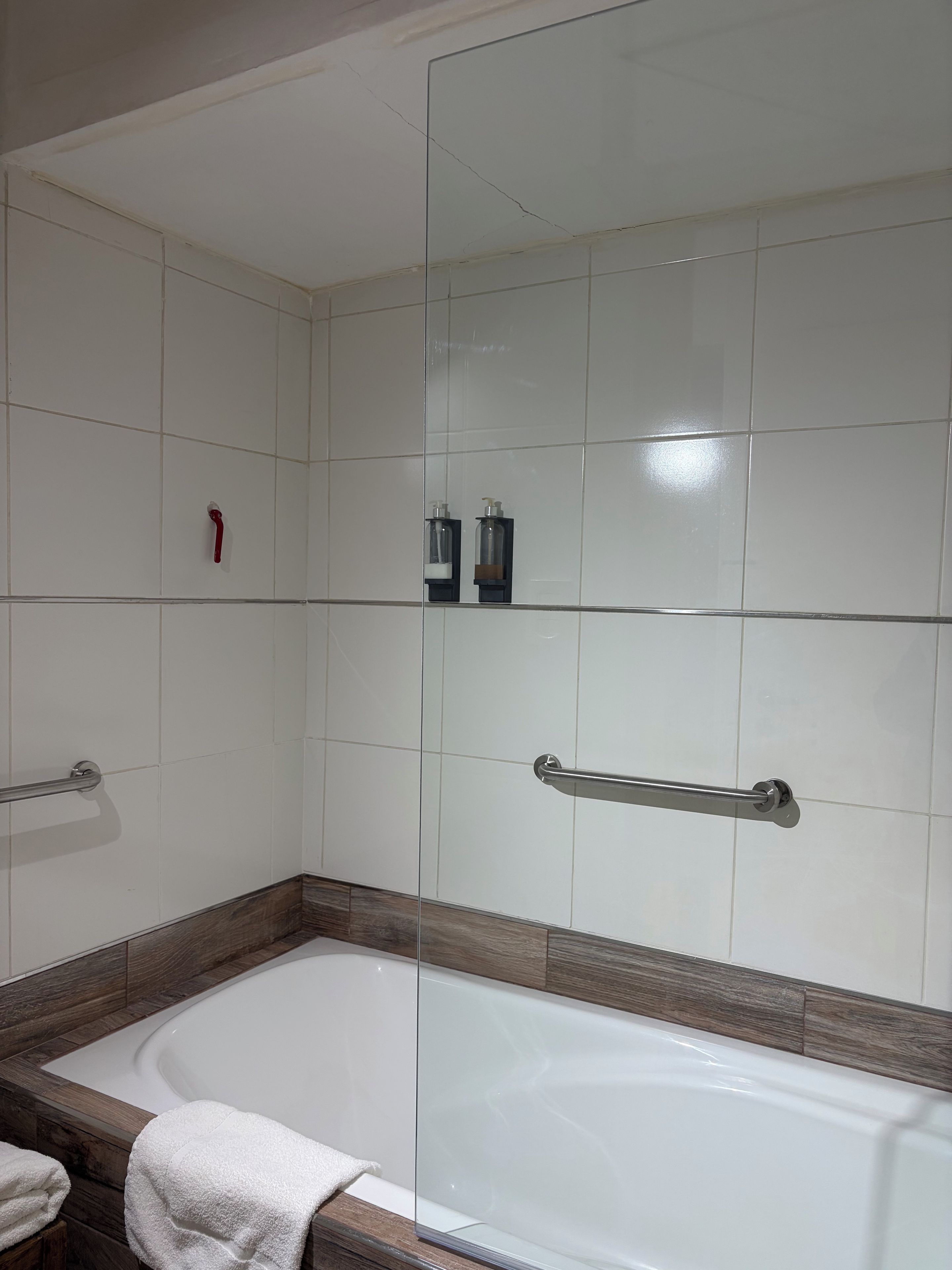 Une salle de bain équipée d’une baignoire, d’une douche à parois de verre et d’une barre d’appui.