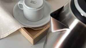 A stainless steel coffee maker, a white table, and a box with a tea set. - COLON 737 (Mendoza)