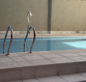 Une piscine avec des échelons métalliques et un mur en arrière-plan.