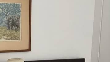 A hotel room with a bed, a nightstand, a lamp, and a framed picture on the wall.