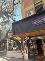 Un escaparate con un letrero de neón, un escaparate de vidrio y un toldo metálico.