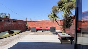Un patio con mobiliario exterior, un kayak y un muro de ladrillo.