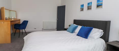 A bedroom with a bed, a desk, a chair, and a radiator.