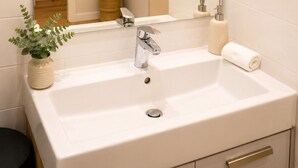 Ein Badezimmer mit einem weißen Waschbecken, einem Spiegel, einer Topfpflanze und einem Handtuch.