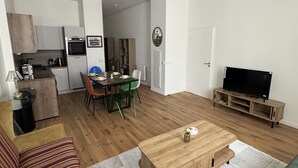 Ein modernes Wohnzimmer mit Sofa, Couchtisch, Fernseher und Essbereich.