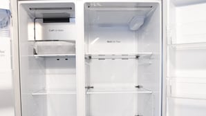 An open refrigerator with multiple shelves and a craft ice maker.