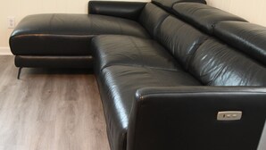 A sectional sofa in a room with wooden flooring and a plain wall.