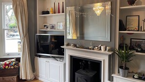 Una sala de estar con chimenea, televisor y candelabro.