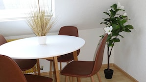A dining area with a round table, six chairs, a potted plant, and a window. - FeWo Moments - 2 min to E-Park (Rust)
