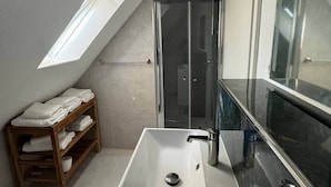 A modern bathroom with a skylight, a walk-in shower, a vanity with a mirror, and a wooden shelf with towels. - FeWo Moments - 2 min to E-Park (Rust)