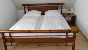 A single bed with a wooden frame and white bedding in a room with white walls and a sloped ceiling. - FeWo Moments - 2 min to E-Park (Rust)