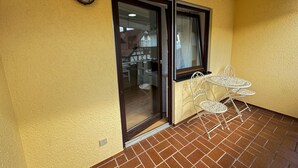 A yellow wall with a sliding glass door, a small white table with chairs, and a metal light fixture. - Central Rust Vacation Rental | 5-minute walk to Europapark (Rust)