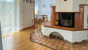 A modern kitchen with a stone fireplace, wooden flooring, and a dining area in the background. - Central Rust Vacation Rental | 5-minute walk to Europapark (Rust)