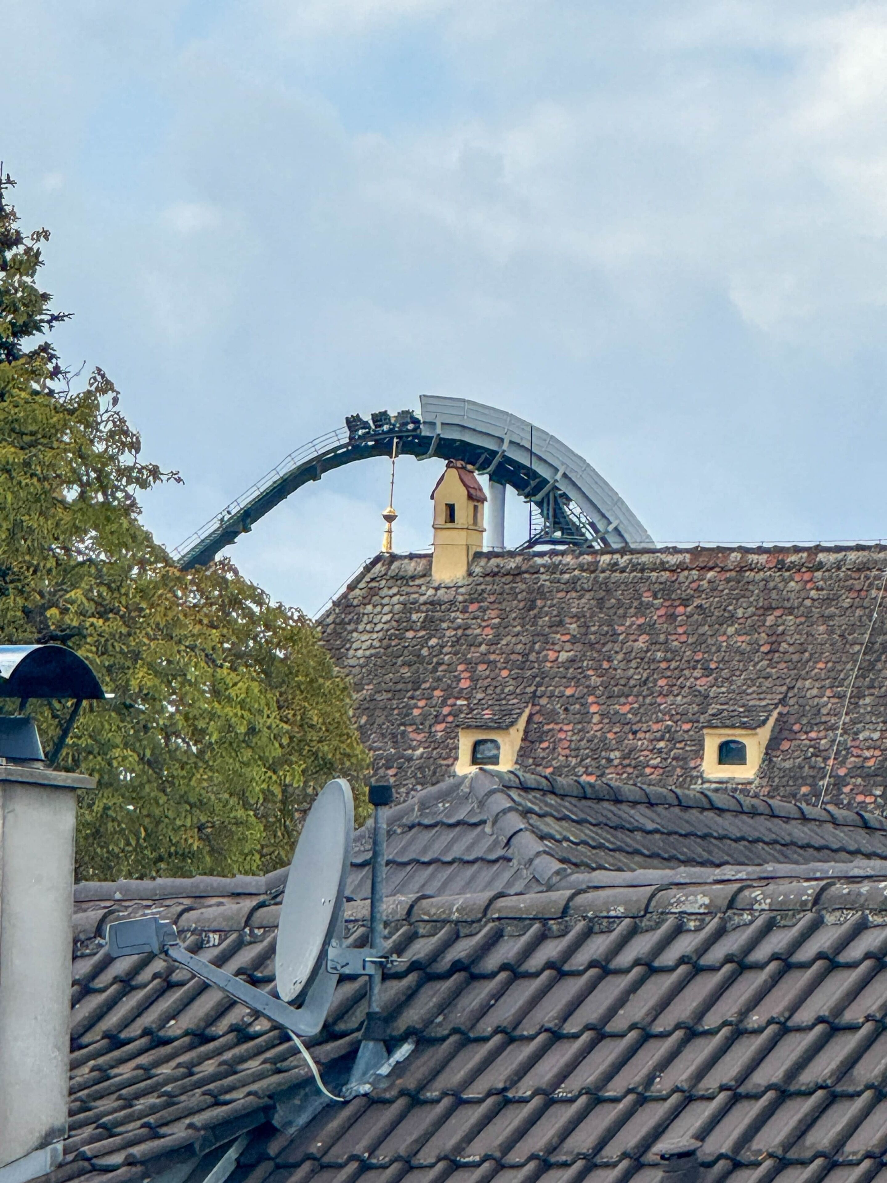A building with a curved metal structure, a satellite dish, and a stone-tiled roof.