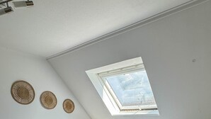 A bedroom with a sloped ceiling, a skylight, a bed with white bedding, two bedside tables, and a small rug. - ONE Vacation Rental - by Europapark (Rust)