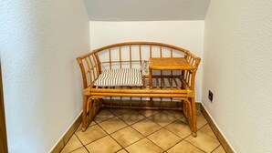 A corner room with a rattan sofa, a small table, and tiled flooring. - ONE Vacation Rental - by Europapark (Rust)