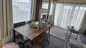 Een knus woongedeelte met een eettafel, een bank, een sofa en een kleine tafel met een afstandsbediening.