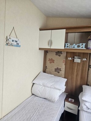 Un dormitorio pequeño con cama, mesita de noche, armario y un cartel en la pared.