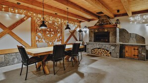 Een houten plafond, een stenen openhaard en een eettafel met stoelen.