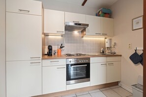 A modern kitchen with white cabinets, a stainless steel oven, and a wooden countertop. - Santhooft E 0303+P-1/251 (Nieuwpoort)