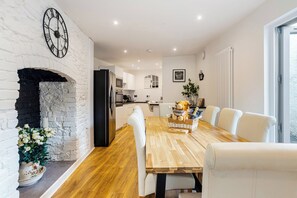 Una cucina moderna con mobili bianchi, un frigorifero nero e un tavolo da pranzo in legno con sedie bianche.
