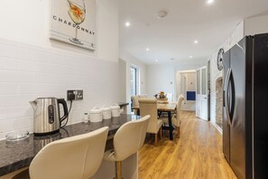 Eine moderne Küche mit Wasserkocher aus Edelstahl, Kaffeemaschine sowie Aufbewahrungsbehältern für Tee und Kaffee auf der Arbeitsplatte.