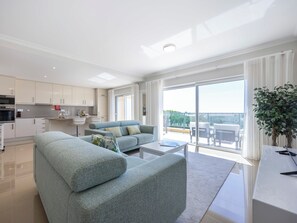 Ein modernes Wohnzimmer mit einer Couch, einem Couchtisch und einem Balkon mit Gartenmöbeln.