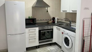 Een praktische keuken met een koelkast, magnetron, oven, wasmachine en een spoelbak.