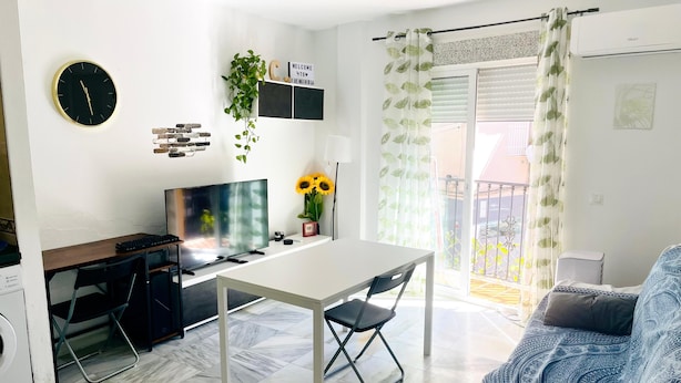 Een moderne woonkamer met een televisie, een eettafel en een bank.