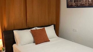 Een hotelkamer met een bed, een hoofdeinde, een nachtkastje, een lamp en een stadsgezichtschilderij aan de muur.