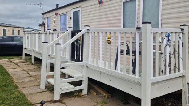 A row of mobile homes with white railings and a staircase leading to the entrance. - Caravan Sleeps 8 - Parking, Pet Friendly (Skegness)