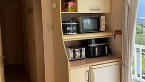 A compact kitchenette with a microwave, toaster, and bread container. - Caravan Sleeps 8 - Parking, Pet Friendly (Skegness)