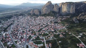 An aerial view of a town with a dense layout of buildings, roads, and a prominent rocky mountain range in the background. - The Patriko - Relaxing Stay With Meteora Views (Kalabaka)