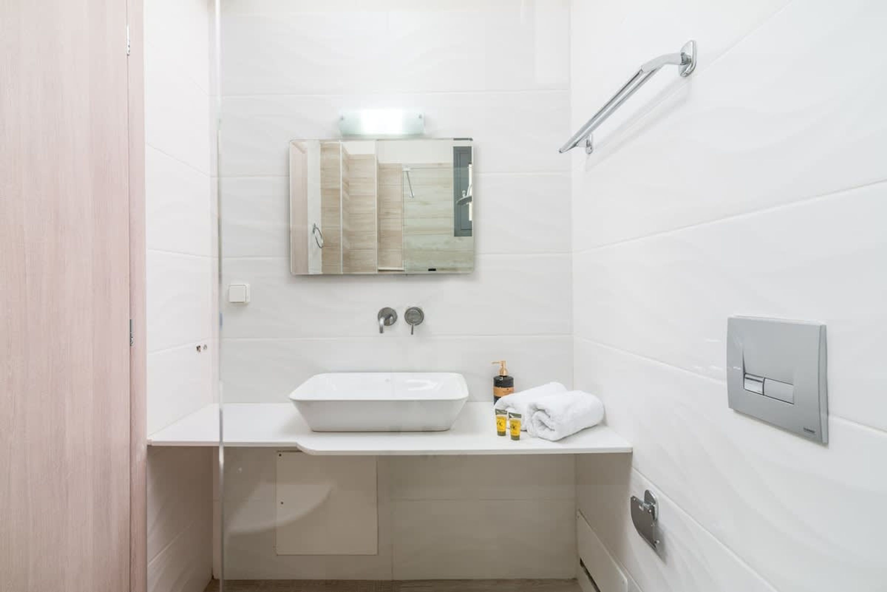Ein modernes Badezimmer mit Waschbecken, Spiegel und Dusche in Weiß.