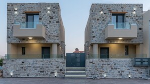 A modern building with stone facade and glass balconies. - Elmara - Beachside Lux Villa 2 With Private Pool (Faistos)