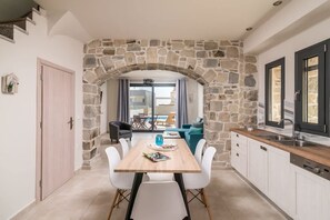A modern kitchen with white cabinets, a wooden countertop, and a stone archway. - Elmara Lux Seaside Villa 1 Private Pool in Crete (Faistos)